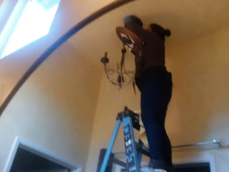 Electrician installing a chandelier in a Hurley residence